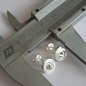Sterling silver spiral stud earrings shown against a measuring caliper for scale - by Two Love Design